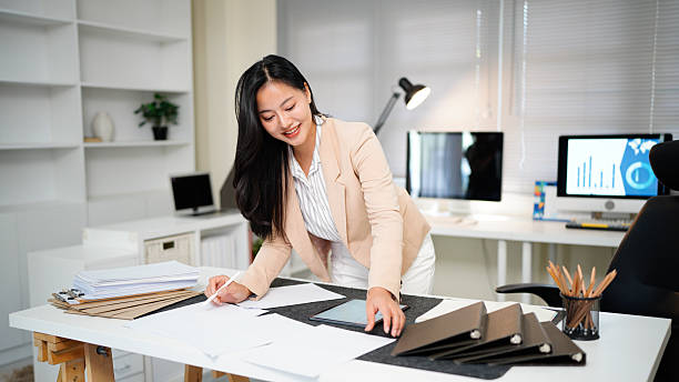 istock Woman reviewing document standing at modern office desk 2255222997