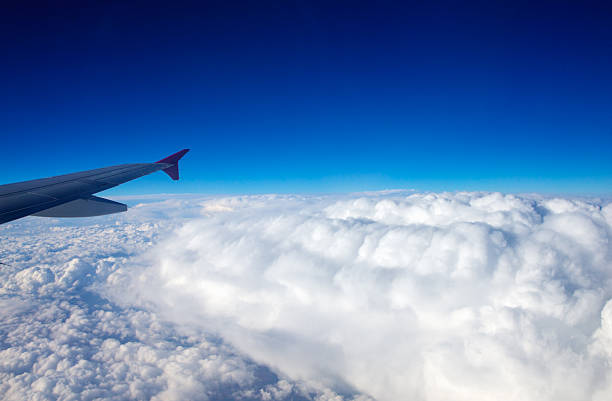 Aerial view of cloud blue sky and plane wing view through the airplane window.
