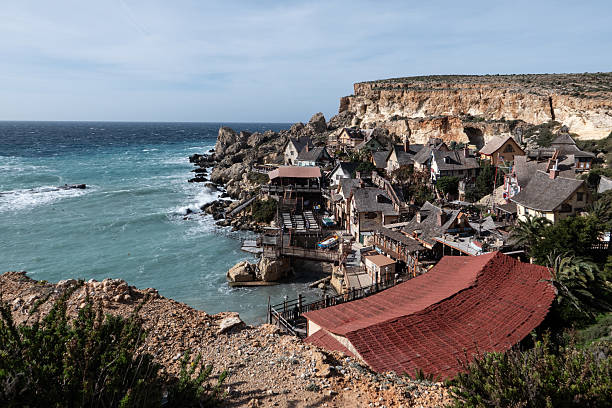 Panoramic view of Popeye Village perched on limestone cliffs above the Mediterranean Sea, showcasing the iconic wooden buildings of the famous film set in Malta. Popeye Village, Malta, January 3, 2026