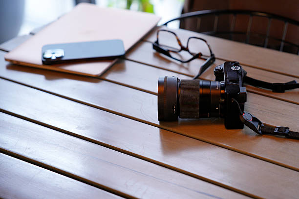 Creative professional workspace with camera, laptop, smartphone, and glasses on a wooden desk