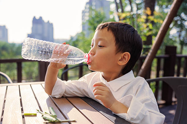 Happy Asian boy drinking water outdoors