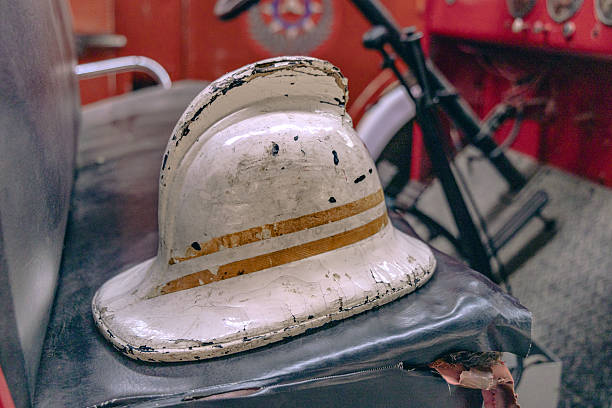 3 firefighter's helmets. One with the black with engine 62. The red with captain, fire department and firefighter's maltese cross coin. The yellow with Lieutenant, 35 and fire-rescue.