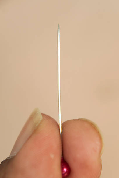 istock Hand Holding Straight Pin with Pink Bead in Close-Up View 2255237675