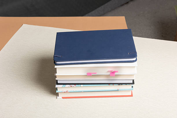 Stack of colorful hardcover notebooks on beige surface in the room