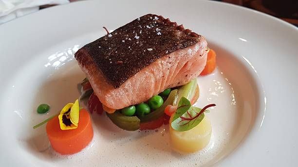 Grilled Salmon Steak with Vegetables and White Sauce on a White Plate