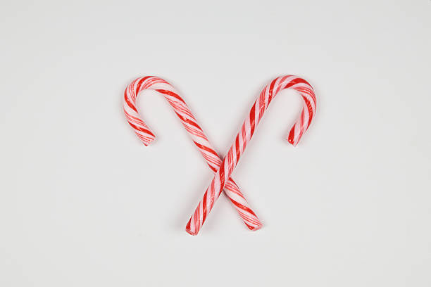 Candy canes with red and white stripes forming patterns and shapes with copy space on a white background.
