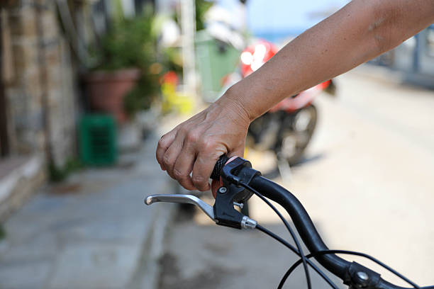 Close Up Of Woman Hand Gripping Bicycle Handlebar And Brake Lever On Urban Street, Showing Cycling Control, Movement, Balance And Everyday Transportation In City Environment.