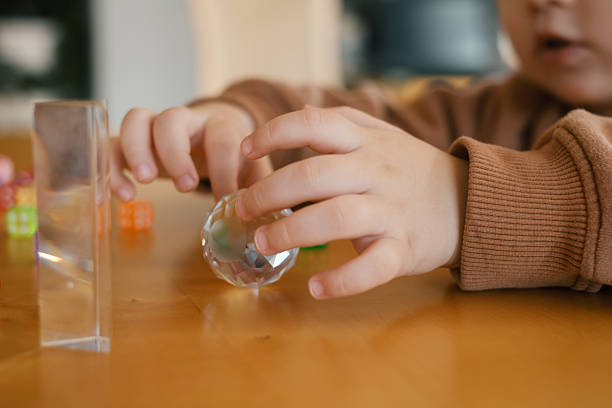 Child hands playing with dice, glass ball and prism, closeup. Tabletop game