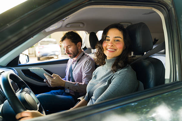 istock Latin woman smiling during driving lesson with instructor at her side, learning to drive and taking a car test 2255259823