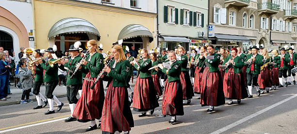 Close-up of people dressed in red and white uniforms holding striped batons during a parade or cultural event.