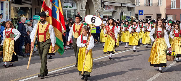 Close-up of people dressed in red and white uniforms holding striped batons during a parade or cultural event.