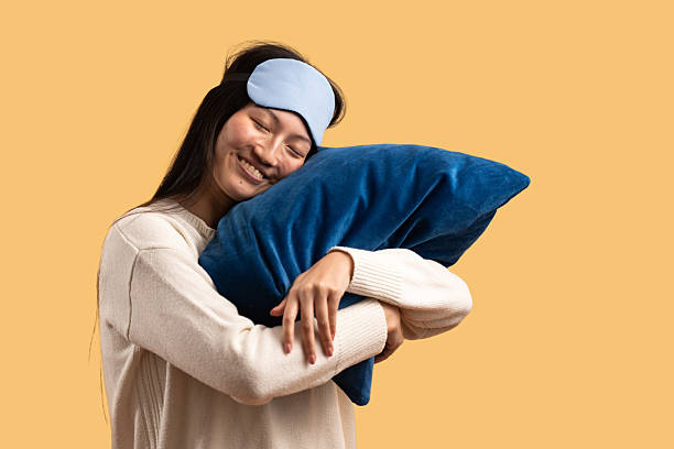 Happy woman embracing her pillow while day dreaming during morning time in a bed.