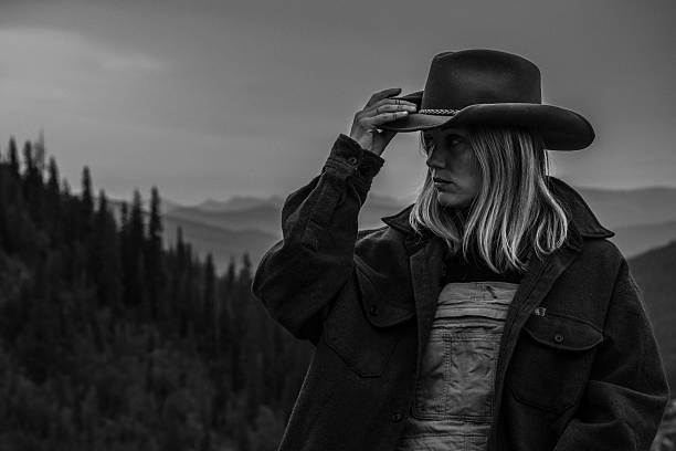 Beautiful, Caucasian Woman with Mountains in Background Standing at Tree Line. Black and White Photography. Copy Space