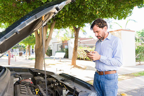 istock Hispanic man feeling worried as his car is having engine trouble, using cell phone to contact roadside assistance or family 2255266061