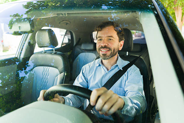 istock Hispanic man safely driving car while commuting, smiling, and looking forward on road during day 2255266217