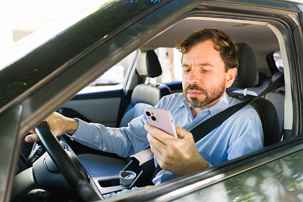 istock Adult driver texting with a mobile phone inside a car, engaging in distracted driving and increasing accident risk 2255266240