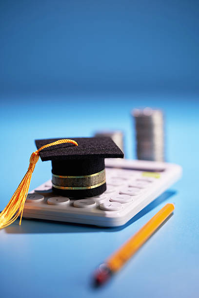 istock small mortarboard on calculator ,pencil and few stack of coins 2255266407