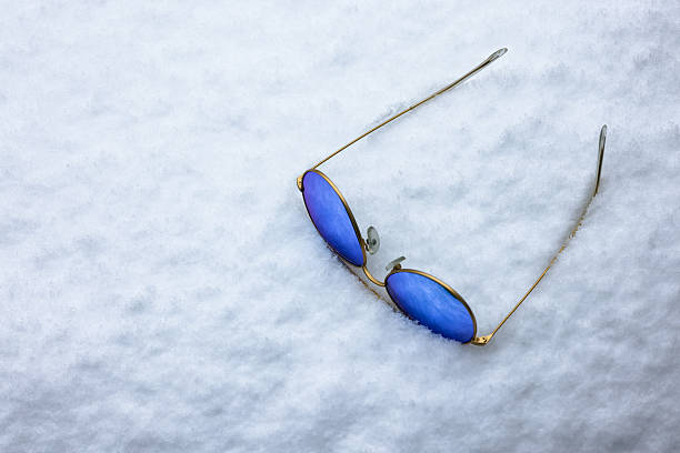Winter vacation. Blue UV sunglasses in snow.