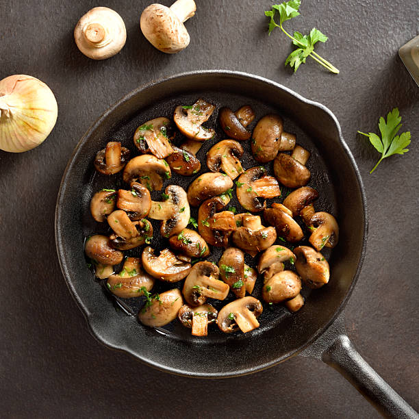 Roasted mushroom in cast iron pan over dark stone background. Vegetarian vegan food concept. Top view, flat lay