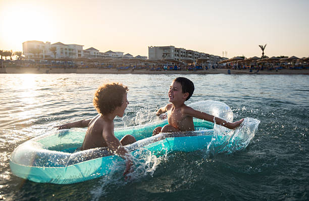 Two multiracial teenage girls are sitting on a sunny beach, enjoying their adventure trip and sharing a moment of joy and friendship. Paracas national reserve