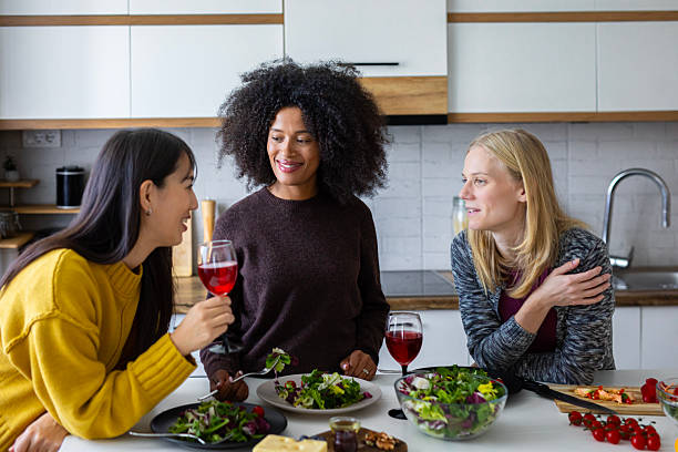 istock Three cheerful women enjoy fresh salad and lively conversation while laughing and relaxing together in a cozy kitchen 2255277434
