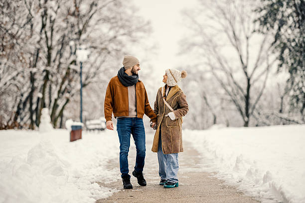 istock Young couple walking hand in hand in snowy park 2255277448