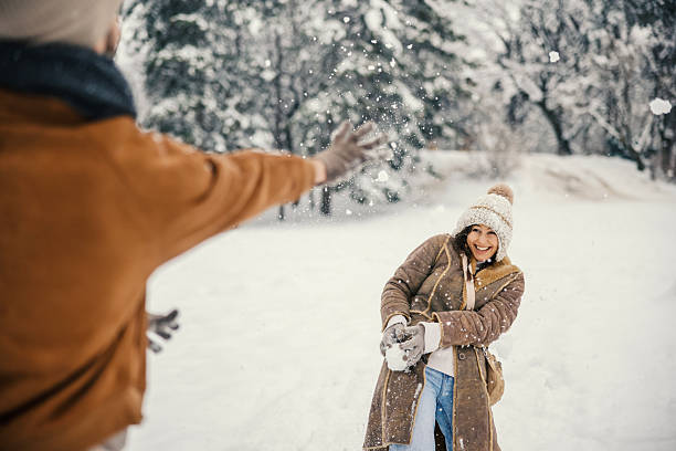 Two young women having fun in the snow, throwing snowballs at each other in a playful snowball fight