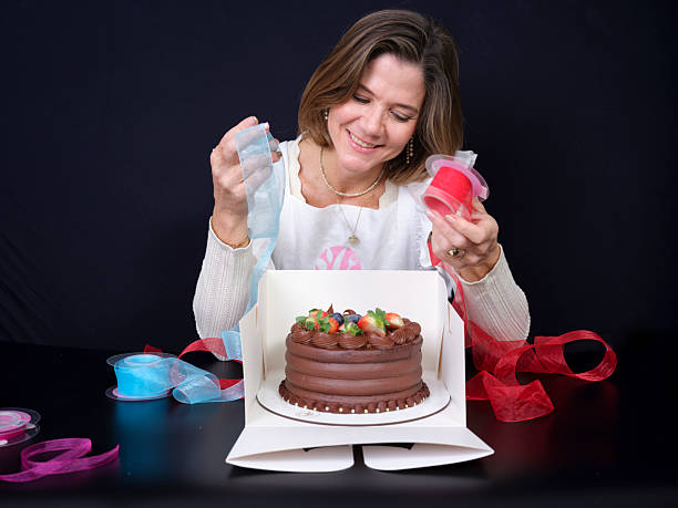 Woman decorating chocolate cake with ribbons for gift