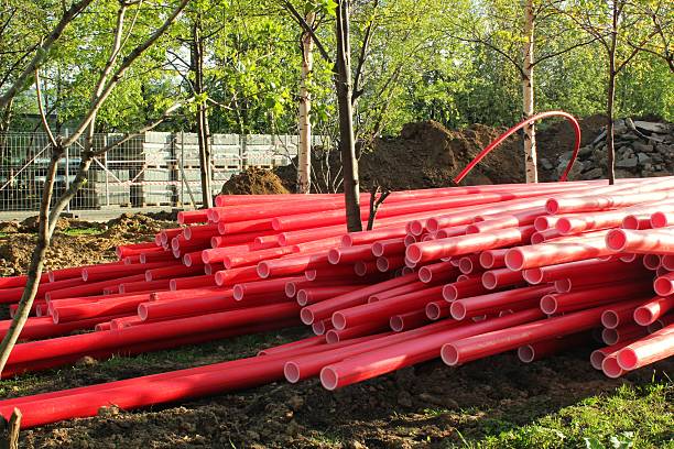 istock Pile of red plastic conduit pipes on a construction site for underground electrical cable or utility installation during urban development project on a sunny day 2255281701