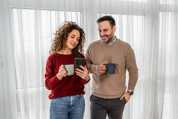 istock Happy couple relaxing at home looking at smartphone 2255284218