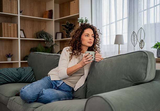 istock Woman relaxing on sofa holding mug thinking 2255284598