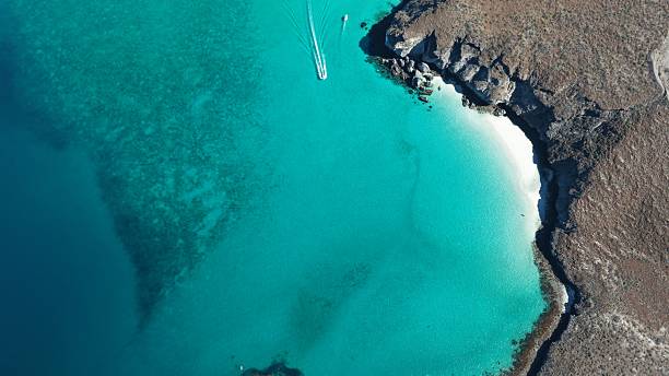 Aerial view of vibrant ocean colors blending from deep blue to turquoise, captured over a pristine seascape. The image showcases the natural beauty of the sea, with gentle waves, shifting tones, and a peaceful coastal atmosphere — a perfect visual for themes of nature, travel, and serenity.