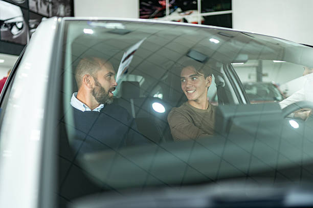 istock Father and son talking while showing a car at car dealership 2255290196