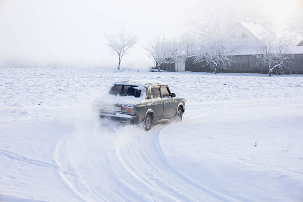 Rear view of an old sedan car drifting in deep snow on a cold winter day