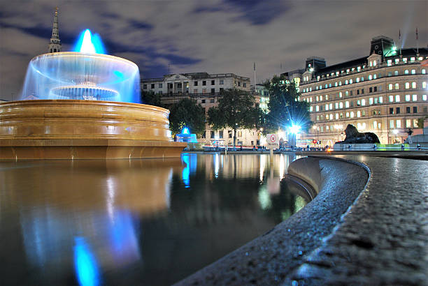 London, UK - September 2, 2011: Londoners dip their feet in Trafalgar Fountain to cool off during an end of summer heatwave. After a 2009 restoration, the fountains can now stream send a 24-meter (80-foot) jet of water into the air, which provides relief for crowds of tourists and locals on a hot day.