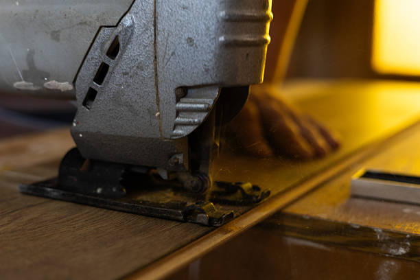 Senior man in a workshop environment operating a woodworking machine to prepare a wooden plank. Manual labor, craftsmanship, and woodworking expertise.