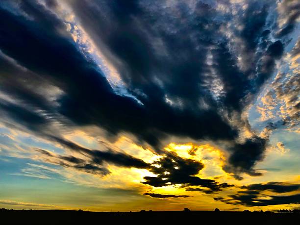 Clouds are filled with light from sunrise breaking. An incoming storm and dawn made striking colors in the sky over the farmland of the Kansas prairie.