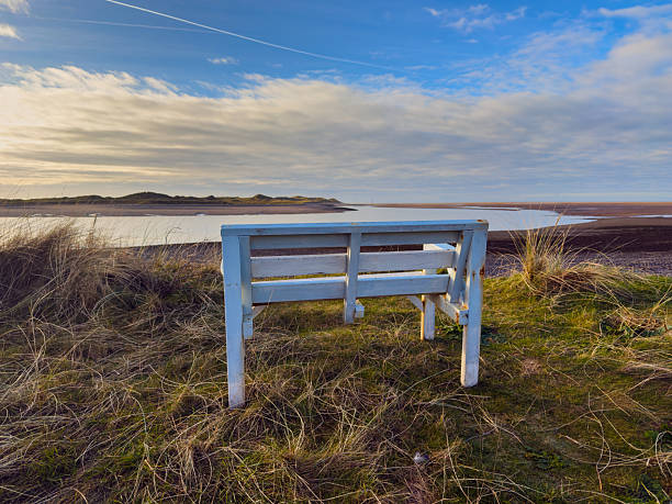 Wooden bench overlooking coastal estuary and sandbanks.