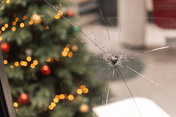 Berlin, Germany – January 2, 2026: Cracked window glass is shown with blurred Christmas lights and decorations visible in the background.