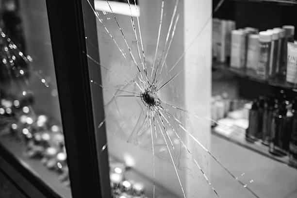 Close-up of a shattered shop window with a bullet hole and radiating cracks following New Year disturbances in Berlin.