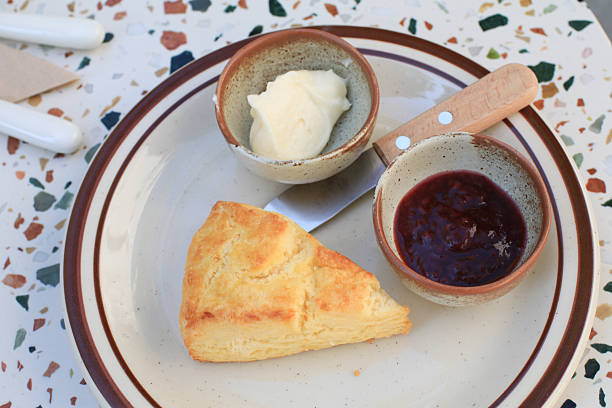 Scones with butter and strawberry jam on marble table. Crumbly texture, slightly sweet. Essential for afternoon tea.