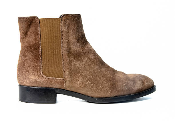 Studio shot of a classic brown suede Chelsea ankle boot with elastic side panel and low block heel photographed in side view isolated on a clean white background suitable for fashion ecommerce footwear catalog and retail marketing use