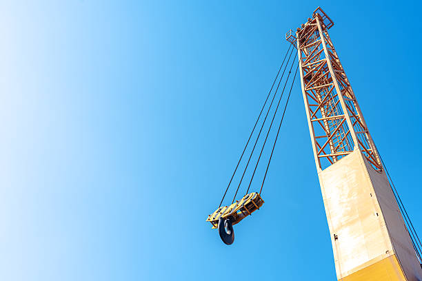 Industrial crane boom and hook against a sunny blue sky