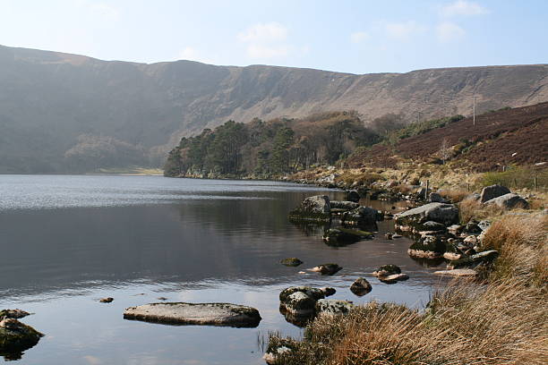 Wide-angle view of Lough Bray in County Wicklow, Ireland, with calm waters, surrounding hills, and scenic countryside. A peaceful and picturesque Irish lake landscape.