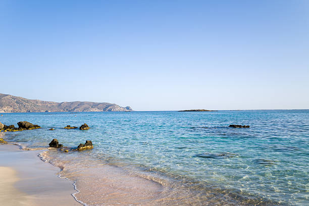 People sunbathing and swimming on a beach on a hot day. View from further away, no recognizable people.