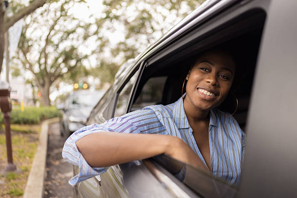 istock Young black woman smiling from car window 2255324005