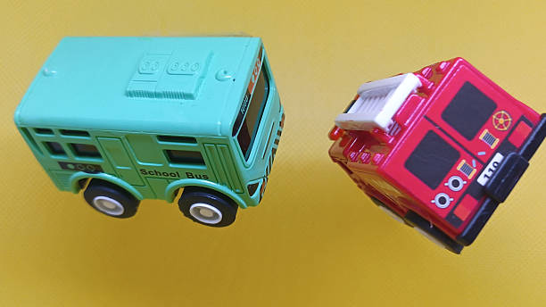 Two toy vehicles, a school bus and fire truck, on a bright yellow background