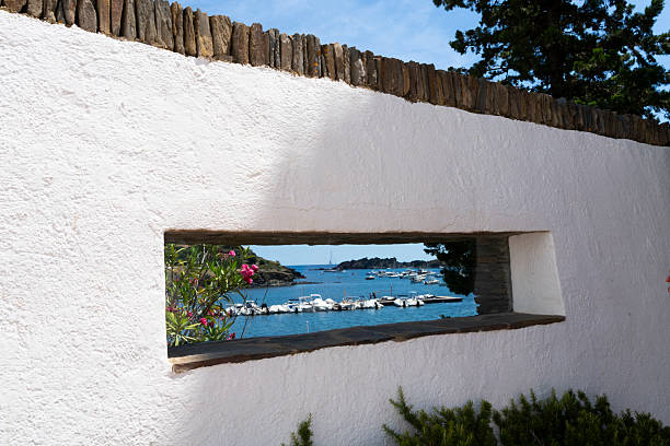 View of boats in the harbor through an open window on an exterior wall of  Salvador Dali 's home where he lived 50 years in the bay of Port Lligat in the small fishing village of Cadaques on the Costa Brava, Girona, Spain