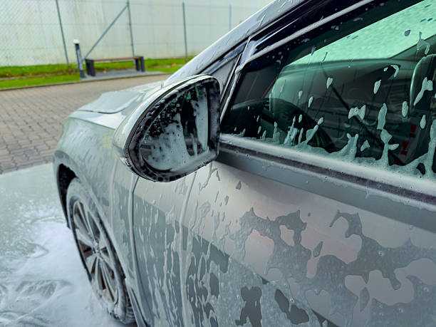 istock Shining silver car covered in soap bubbles during midday wash at a clean garage in a bustling urban area 2255344065