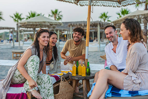 istock Friends laughing enjoying refreshing drinks on beach vacation 2255344422